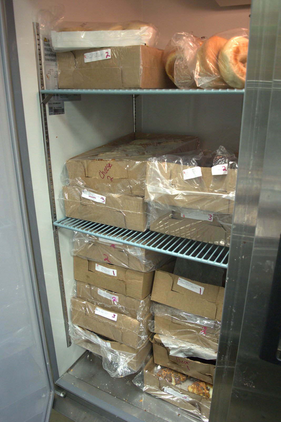 Bottom shelf shows torn boxes with exposed/leaking pastries sitting on the fridge floor (cross-contamination risk)