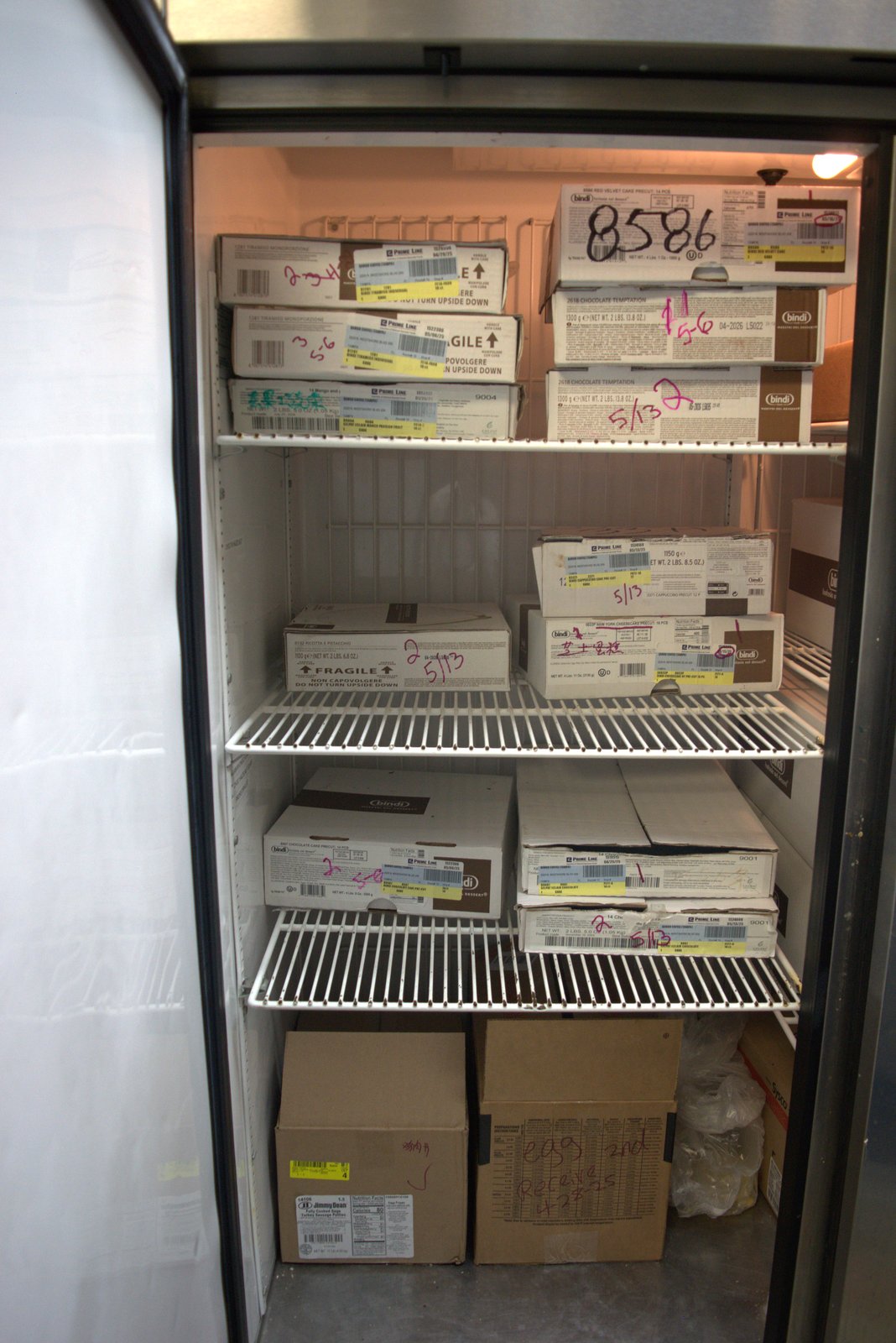 BOH freezer — Bindi cake boxes stamped 5/13, 5/6 and 'egg 2nd Receive 4/28/25': long-stored product mixed with new