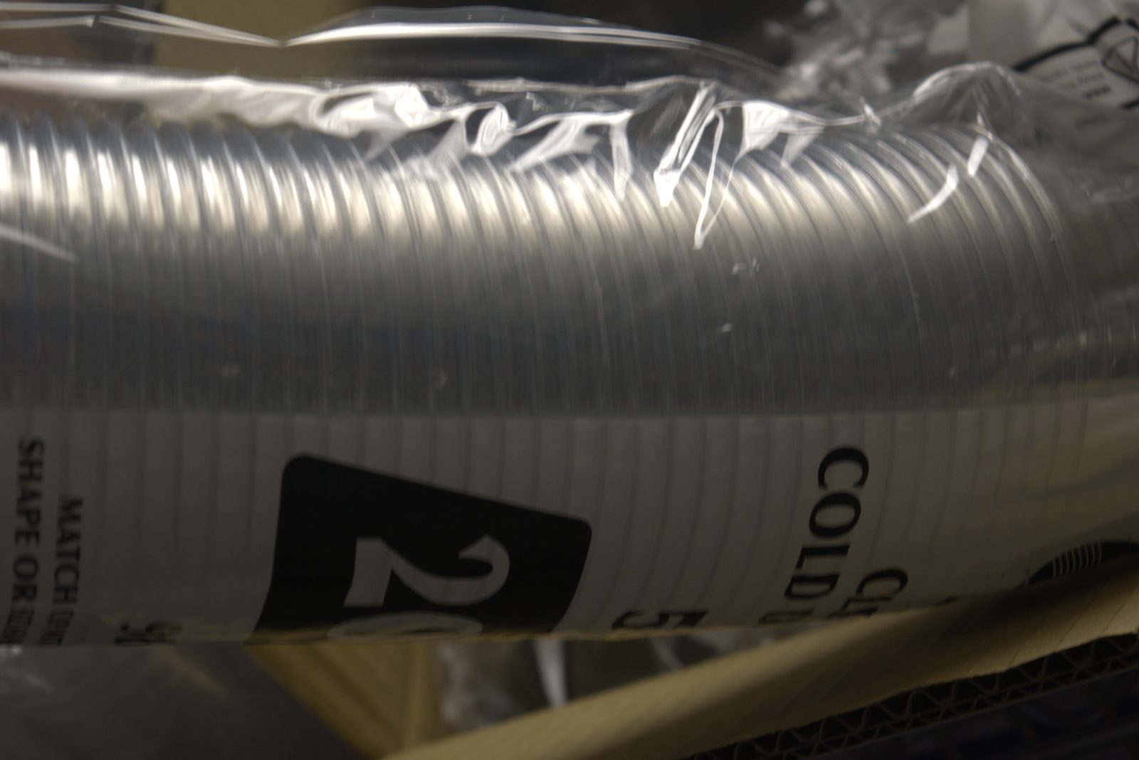 Unbranded 'CLEAR COLD' cup sleeve — generic non-Qargo packaging stored loosely in a cardboard box
