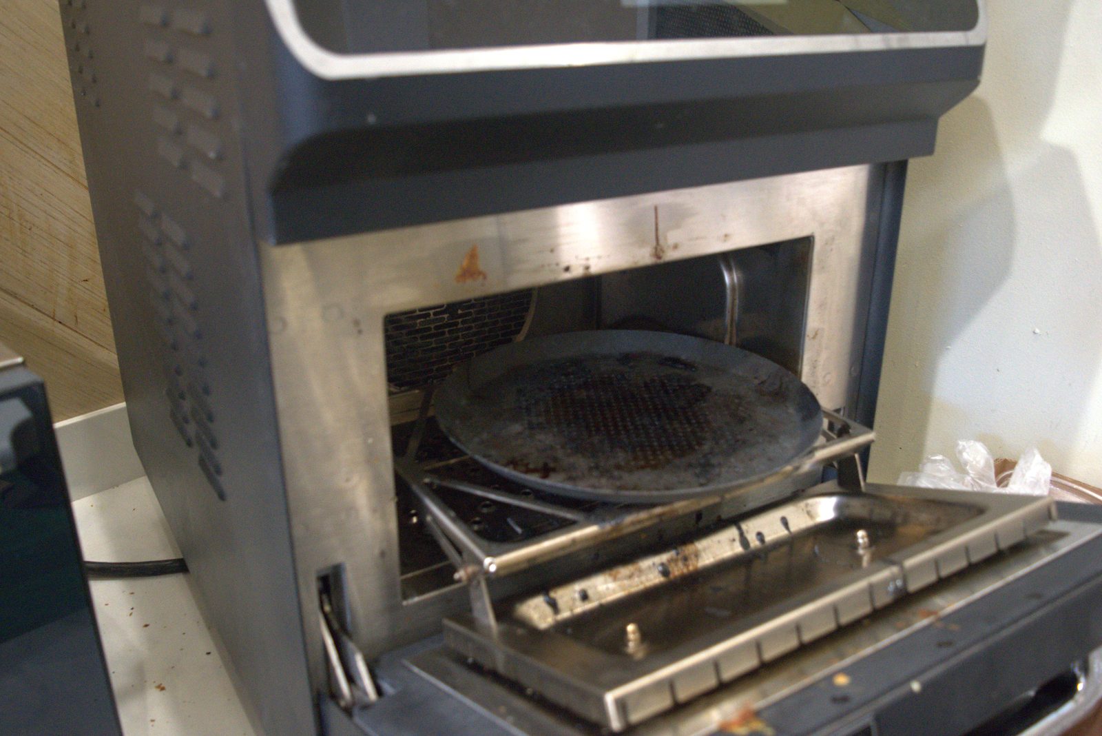 Merrychef high-speed oven — interior pan scorched and encrusted with carbonized food residue