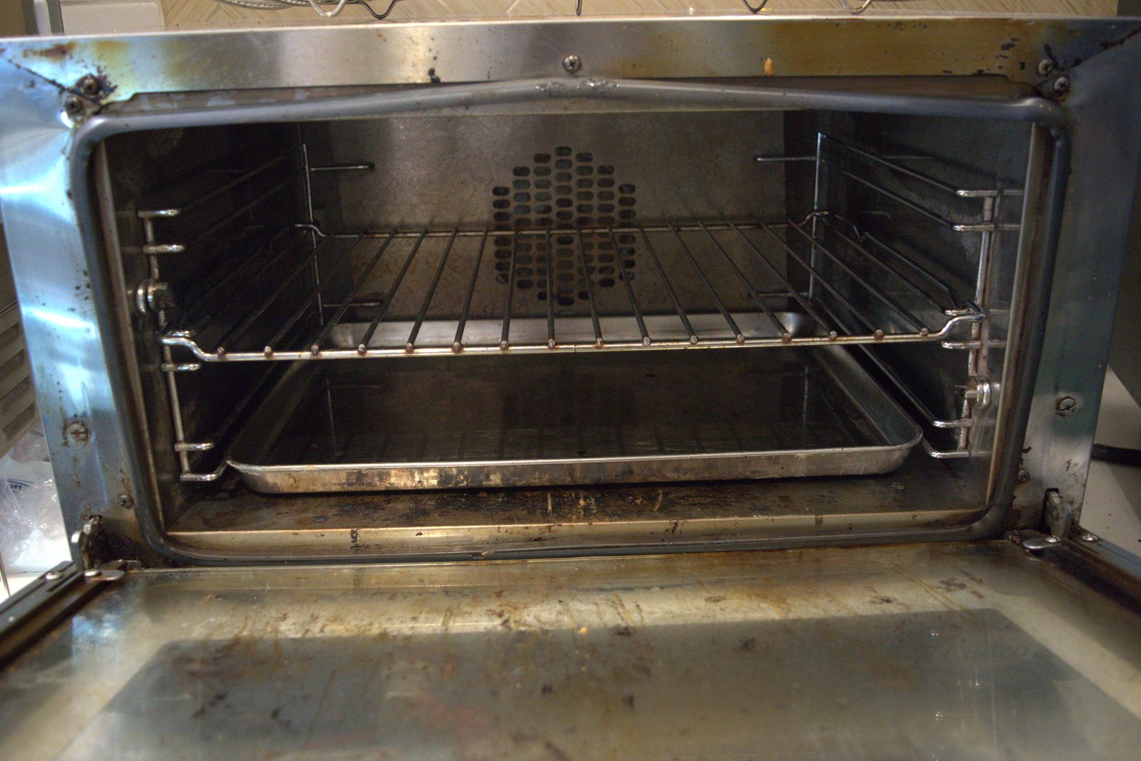 Convection oven interior — racks, walls and bottom plate caked with baked-on grease and food carbon