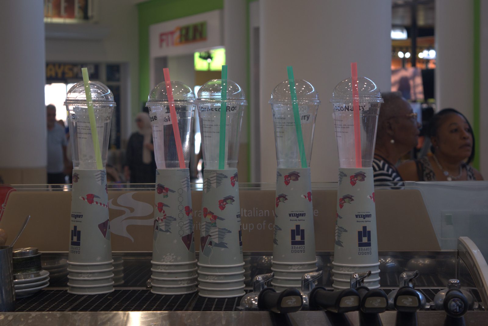 Pre-poured drinks served to mall customers in 'Qargo Coffee — Proudly Serving LAVAZZA' co-branded cups