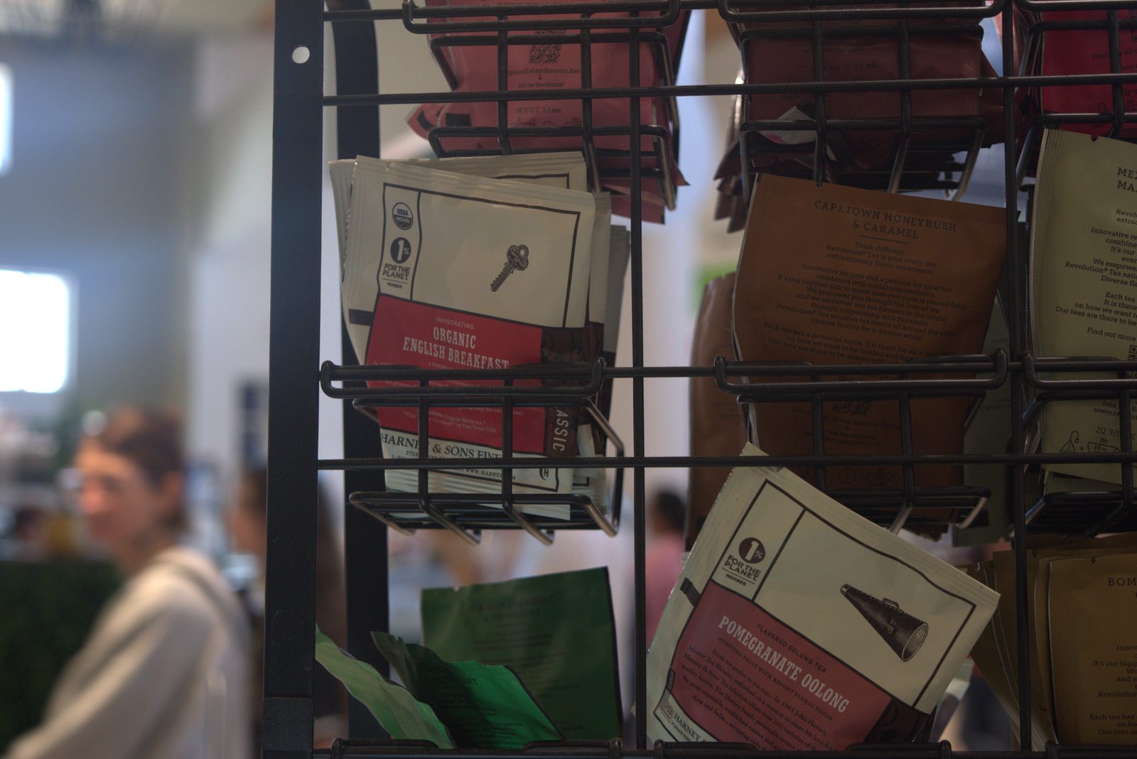 Same tea caddy, wider view — multiple unauthorized tea brands (Harney & Sons English Breakfast & Pomegranate Oolong, Revolution Tea Capetown Honeybush & Caramel) stocked at the customer-facing tea bar