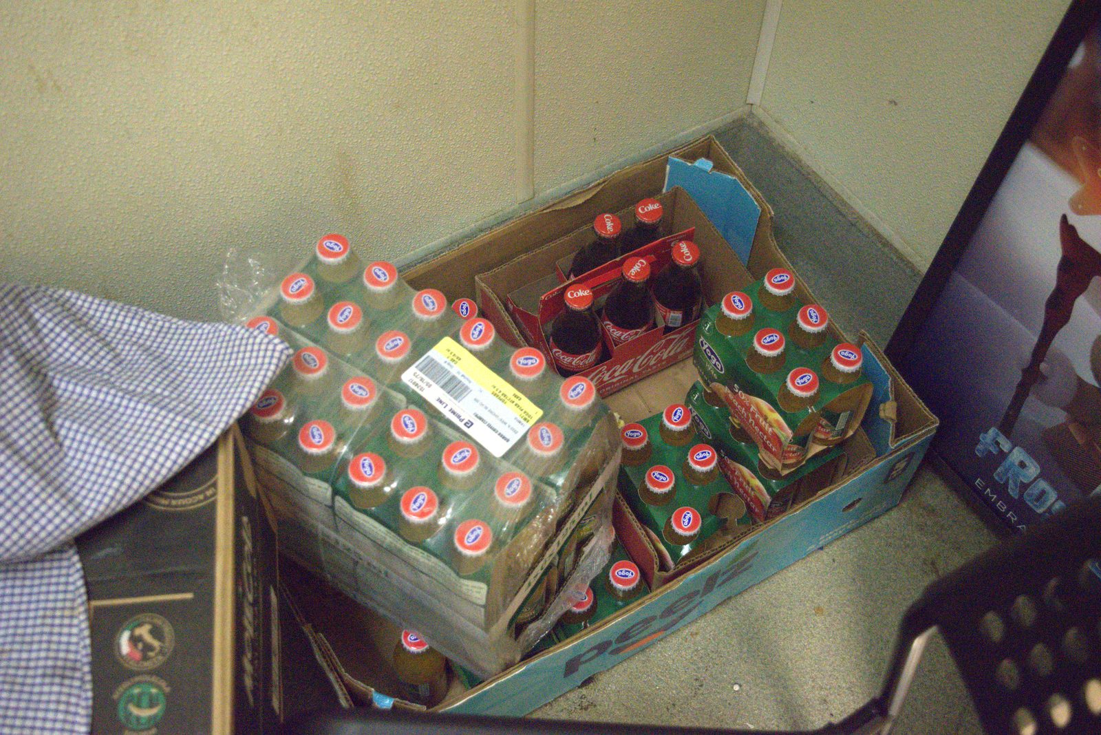 Storage area floor — Italian-import 'Yoga' fruit nectar and Coca-Cola glass bottles in torn cases on a stained floor
