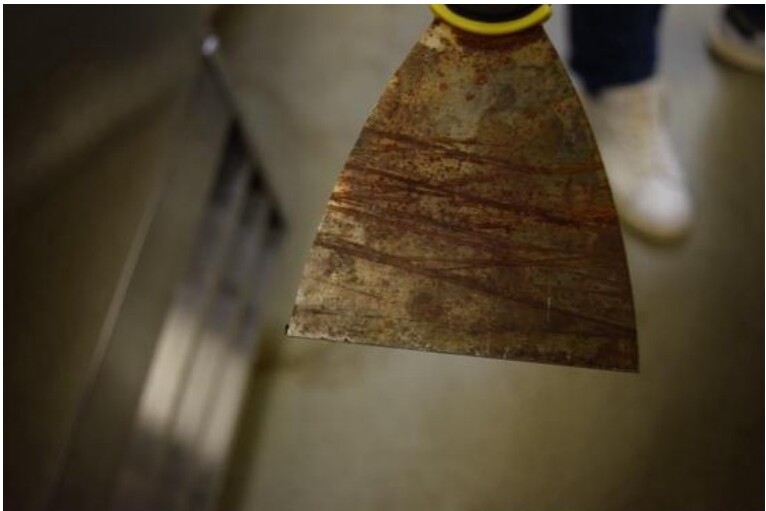 Rusted scraper tool in active use